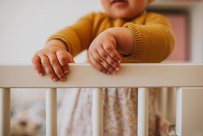 Midsection of baby girl standing in crib at home