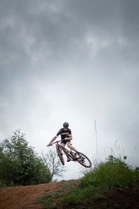 Low angle view of man jumping against sky