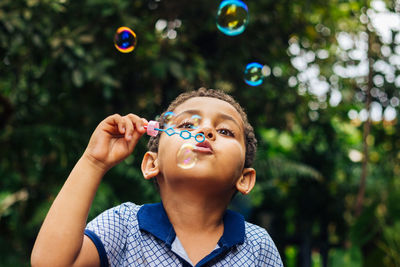 Boy blowing bubbles in park