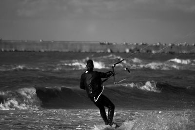 Man kiteboarding on sea against sky