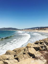 Scenic view of beach against clear blue sky