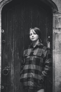 Portrait of young woman standing against wall