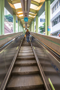 Rear view of man walking on escalator