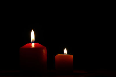 Close-up of burning candles against black background