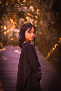 Portrait of woman standing against tree