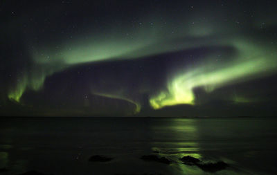 Scenic view of aurora borealis over sea at night