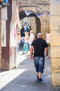 Rear view of people walking on road in city