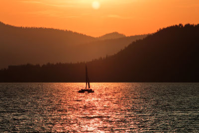 Silhouette sailboat sailing on sea against sky during sunset