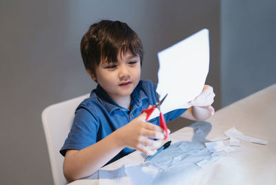 Boy looking away while sitting on table