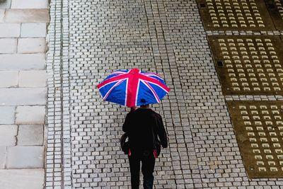 Rear view of woman walking on umbrella during rainy season