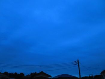 Low angle view of electricity pylon against blue sky