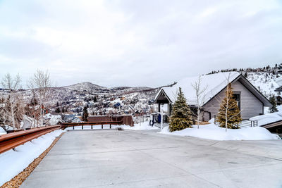 Houses on snow covered field by building against sky