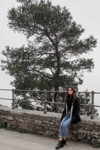 Portrait of young woman sitting against tree