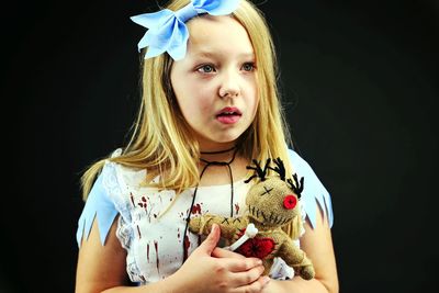 Close-up of cute girl holding toy against black background