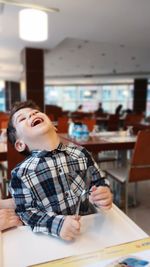 Boy laughing while sitting at table in school