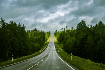 Road amidst trees in forest against sky