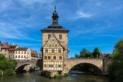 Arch bridge over river amidst buildings against sky