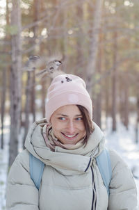 Girl in winter clothes smiles and feeds the birds from the head in the park