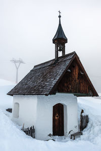 House on snowy field against clear sky during winter