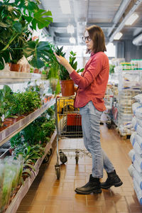 Side view of woman with arms raised in store