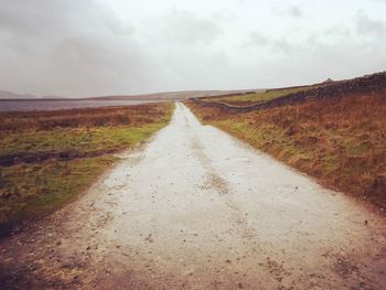 Road amidst field against sky