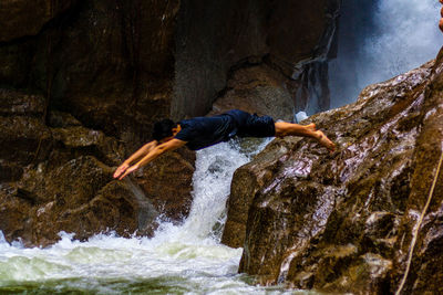 Side view of man jumping in river