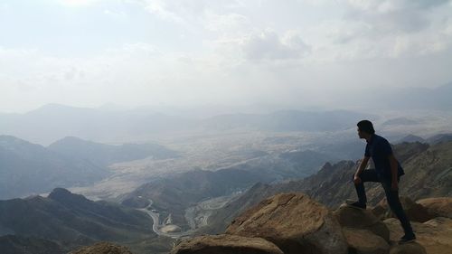 Rear view of man looking at mountains against sky