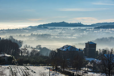 Scenic view of snow covered houses by trees against sky