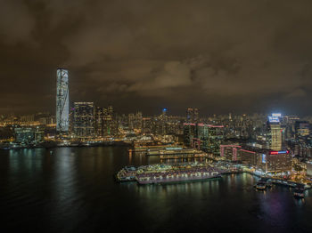 Illuminated city by river against sky at night