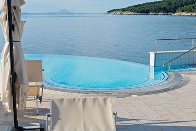 Swimming pool by sea against blue sky