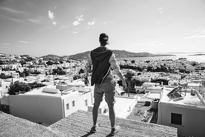 Rear view of man standing on terrace in city during sunny day