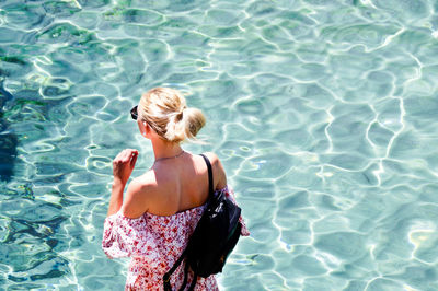 Rear view of woman standing in swimming pool