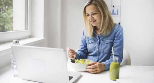 Mid adult woman looking away while sitting on table