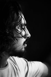 Side view of thoughtful young man looking away against black background