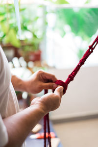 Close-up of hand weaving macramé hanging planter.