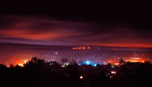 High angle view of illuminated cityscape against sky at night