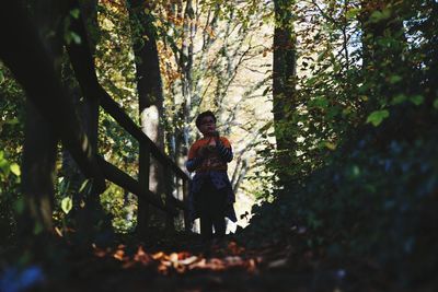 Surface level image of boy standing in forest
