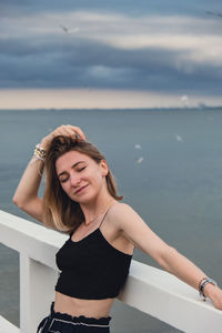 Young woman standing on wooden pier blurred beachside background. attractive female enjoying the sea