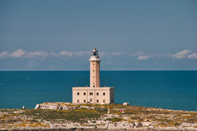 Lighthouse by sea against sky