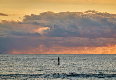 Silhouette people by sea against sky during sunset