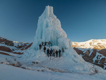 Group of people on snowcapped mountain against sky