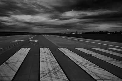 View of airport runway against cloudy sky