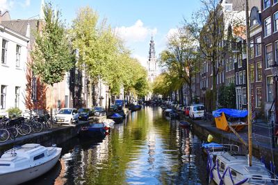 Boats moored in canal amidst buildings in city