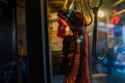 Close-up of meats hanging for sale in market at night