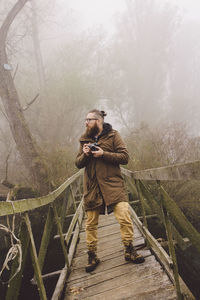 Man standing on footbridge during foggy weather