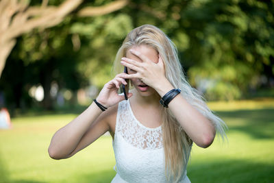 Frustrated woman talking on mobile phone at park
