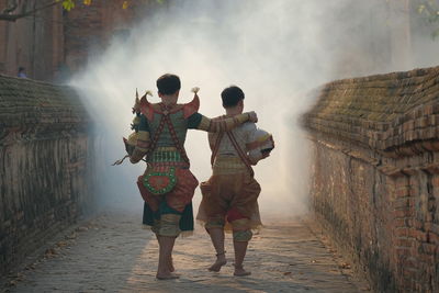 Rear view of people in costume walking on walkway