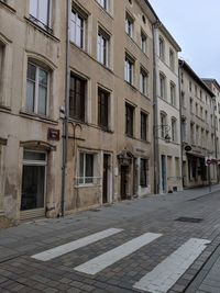 A pedestrian crossing in front of old weathered buildings in nancy, france. 