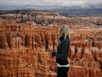 Woman looking away while standing against rock formation