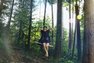 Portrait of cute little girl on swings in forest